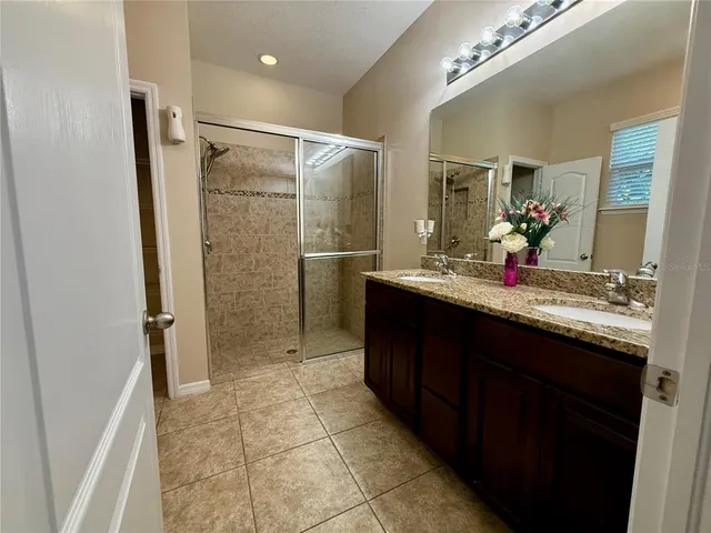a bathroom with a granite countertop sink a mirror and shower
