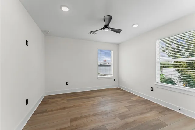 a view of empty room with wooden floor and fan