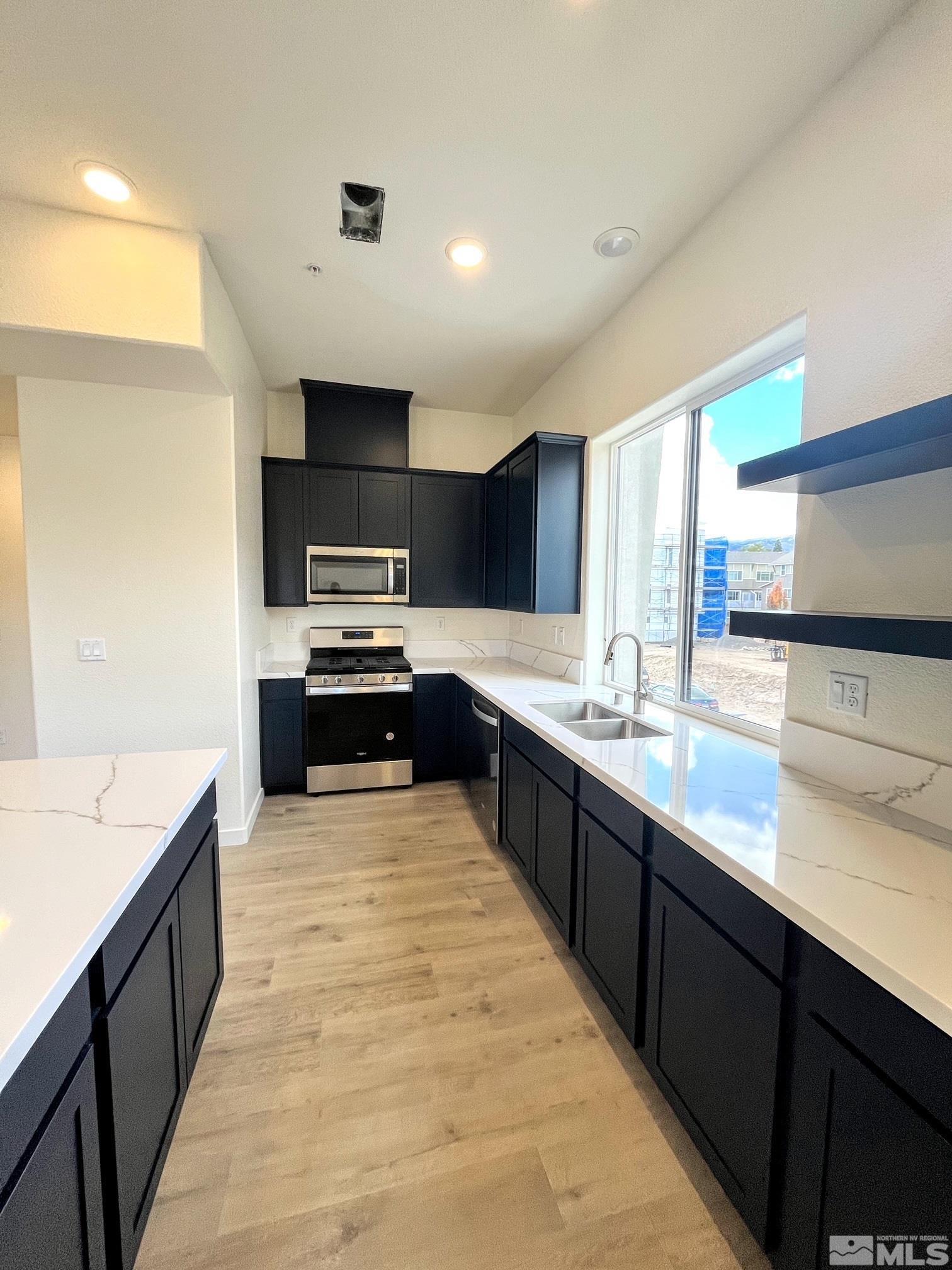 156 Rissone Lane, Unit LOT 33 Reno, NV 89503 - Photo 7 of 21 a large kitchen with granite countertop lots of counter top space and stainless steel appliances