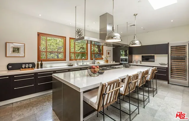 a kitchen with a stove a sink dishwasher a dining table and chairs with wooden floor