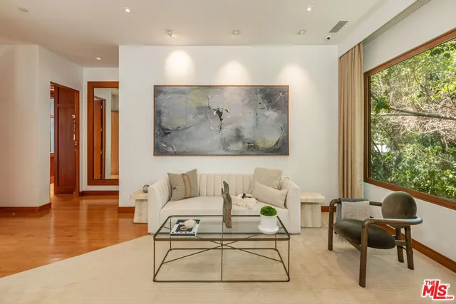 a living room with furniture a large window and wooden floor