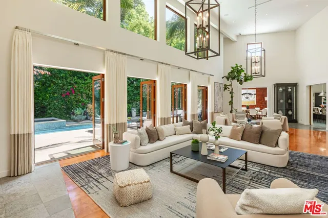 a living room with furniture large windows a rug and a chandelier