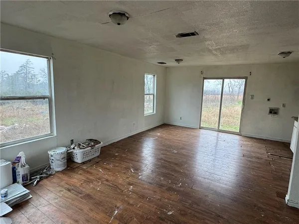 a view of an empty room with a window and wooden floor