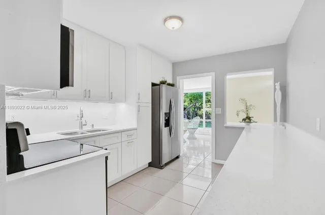 a large white kitchen with a sink and refrigerator