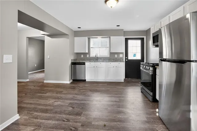 a kitchen with stainless steel appliances granite countertop a refrigerator a stove and a sink