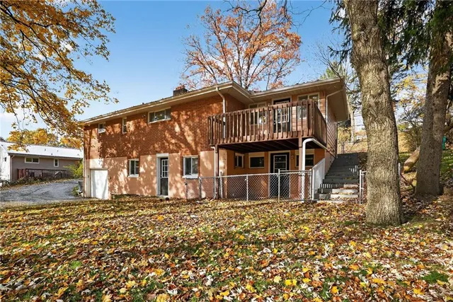 a front view of a house with a large tree