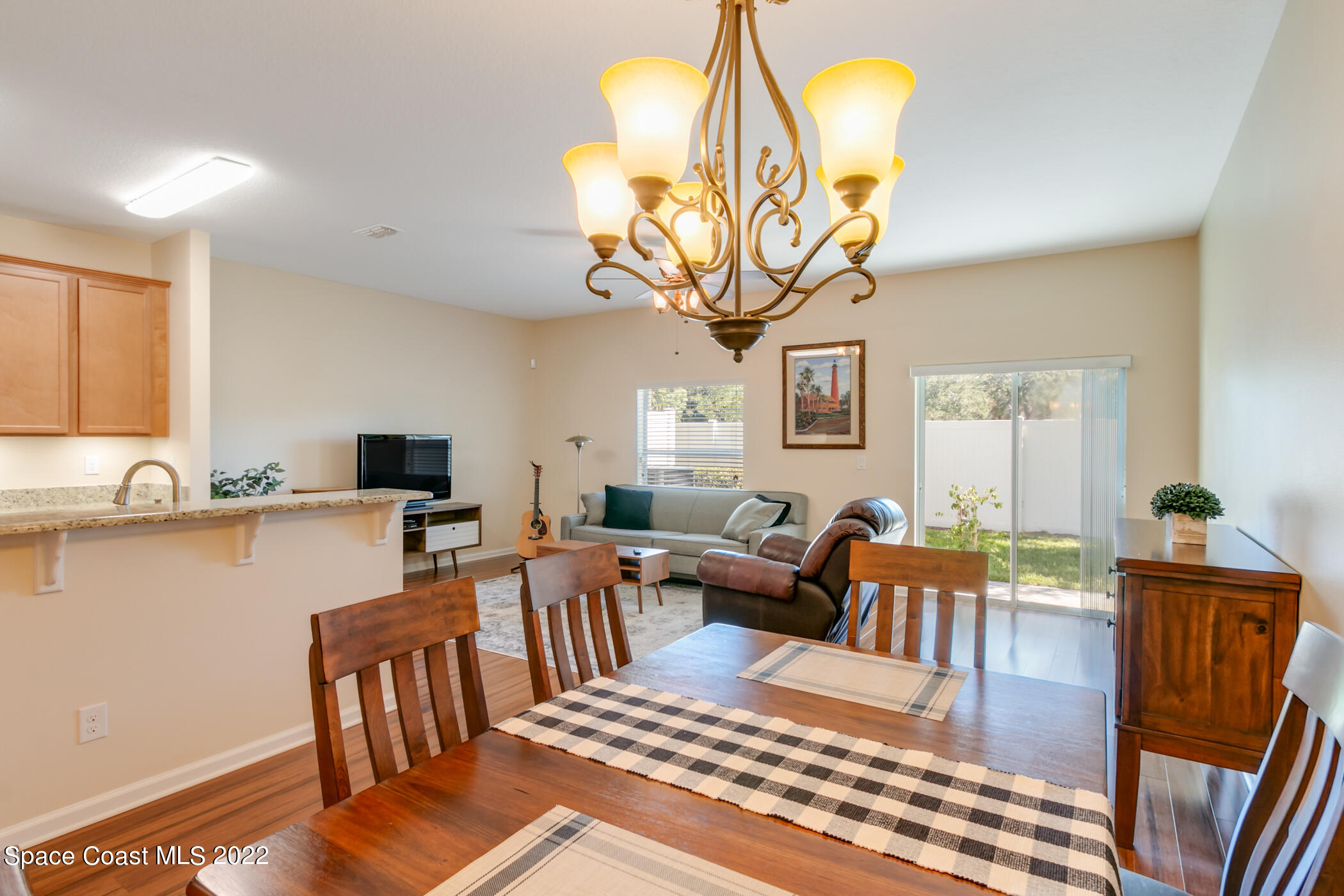 2525 Revolution Street, Unit 104 Melbourne, FL 32935 - Photo 17 of 37 a view of a dining room with furniture a chandelier and wooden floor