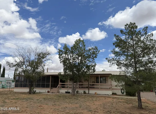 a front view of a house with a yard and a large tree