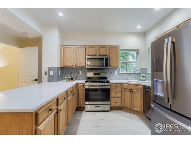 a kitchen with stainless steel appliances granite countertop a stove a sink dishwasher a refrigerator and a microwave