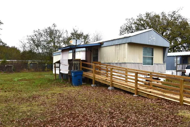 a backyard of a house with wooden fence and large trees