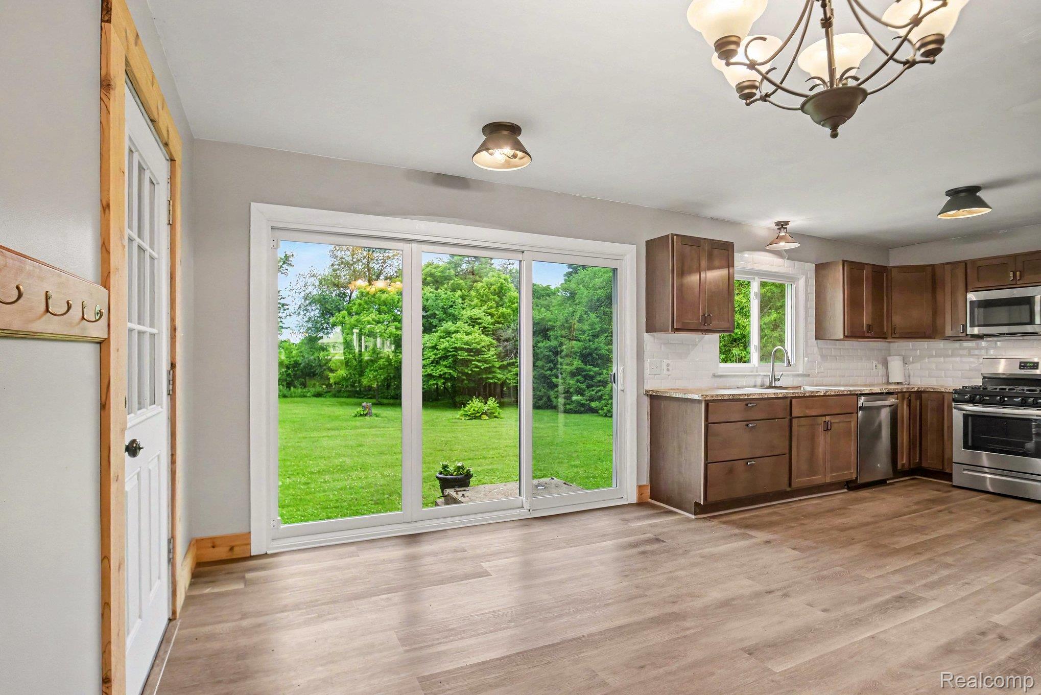 2487 North Lapeer Road Lapeer, MI 48446 - Photo 5 of 16 Spacious kitchen featuring wood-finish flooring, dark wood cabinetry, stainless steel appliances, and a subway tile backsplash