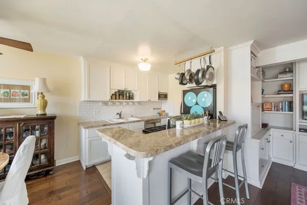 a kitchen with stainless steel appliances granite countertop a stove top oven a sink a dining table and chairs with wooden floor