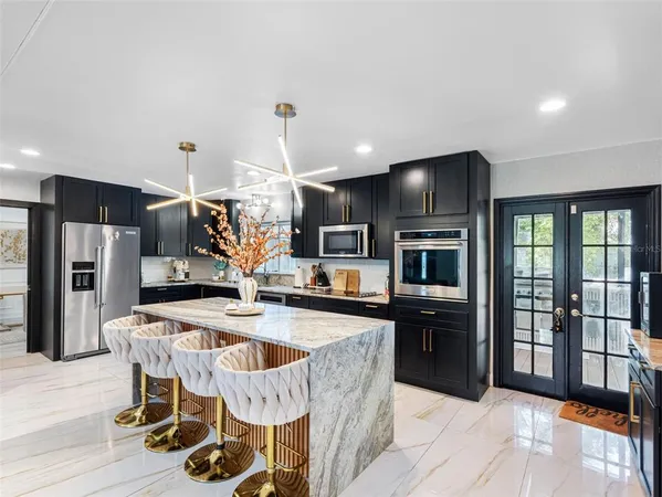a kitchen with stainless steel appliances kitchen island granite countertop a sink refrigerator and cabinets