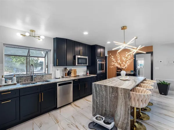 a kitchen with stainless steel appliances granite countertop a sink stove refrigerator and cabinets