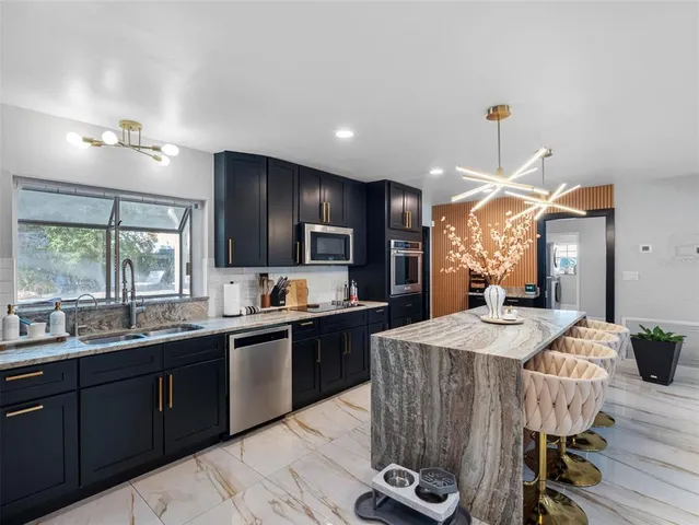 a kitchen with stainless steel appliances granite countertop a sink stove refrigerator and cabinets