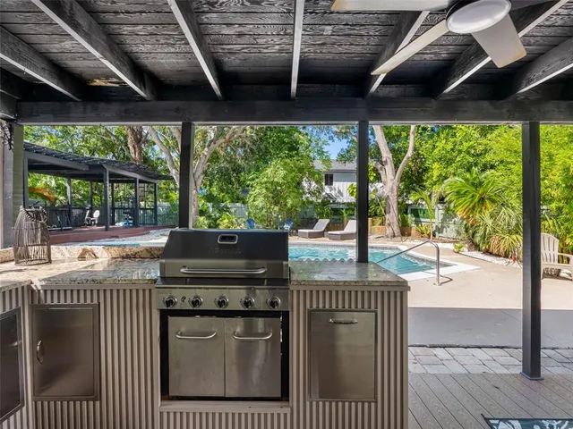 a view of a backyard with table and chairs under an umbrella with a large tree