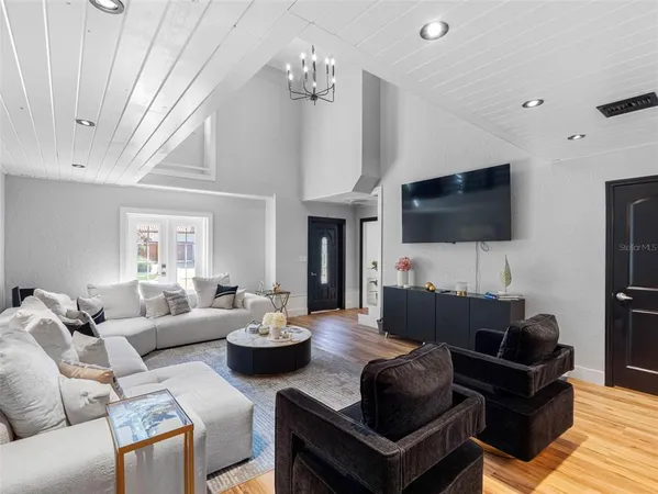 a living room with furniture a flat screen tv and a chandelier