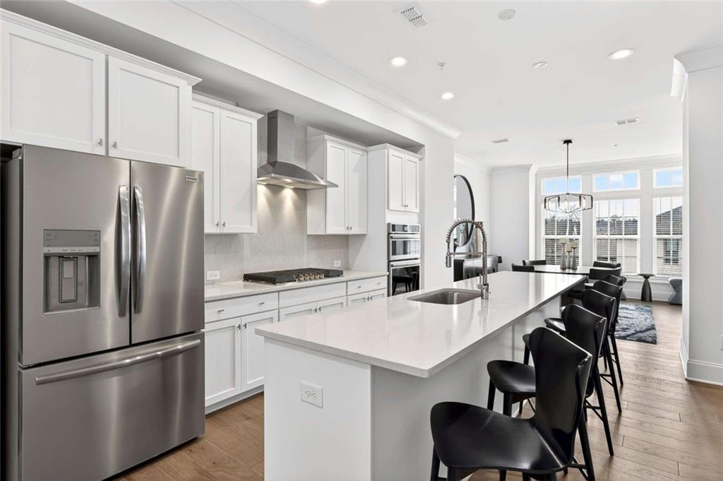 6786 Encore Boulevard Atlanta, GA 30328 - Photo 8 of 31 a kitchen with stainless steel appliances a refrigerator a sink a stove a table and chairs