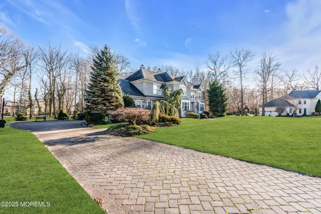 a view of a big house with a big yard and large trees