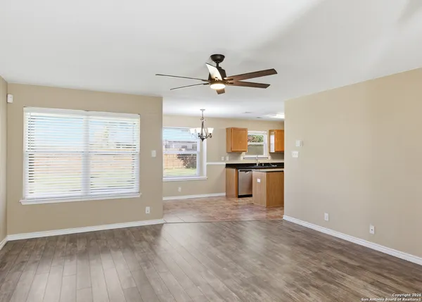 a view of an empty room with a kitchen and wooden floor