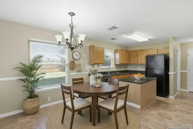 a dining room with wooden floor a chandelier a wooden table and chairs