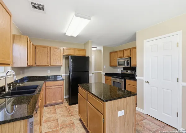 a kitchen with granite countertop a refrigerator stove and sink