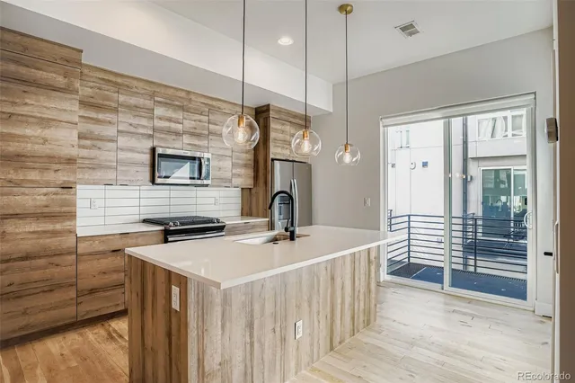 a kitchen with stainless steel appliances granite countertop a sink a stove and a wooden floor