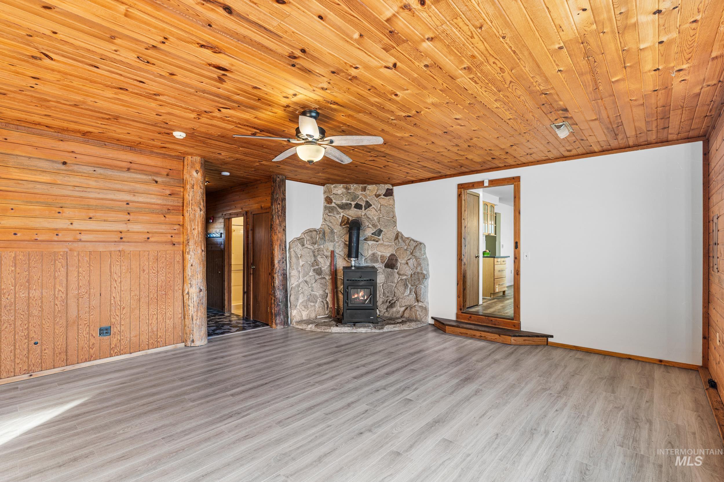 1212 East Ustick Road Caldwell, ID 83607 - Photo 27 of 50 Unfurnished living room with a wood stove, wooden walls, wood finished floors, ceiling fan, and wood ceiling