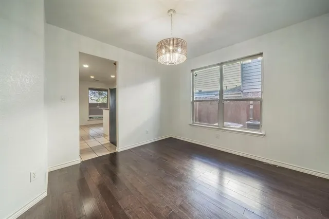 an empty room with wooden floor chandelier and windows