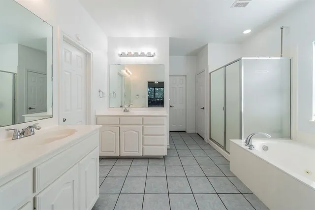 a spacious bathroom with a double vanity sink mirror and bathtub