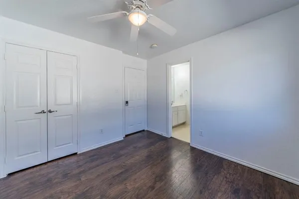 an empty room with wooden floor and fan