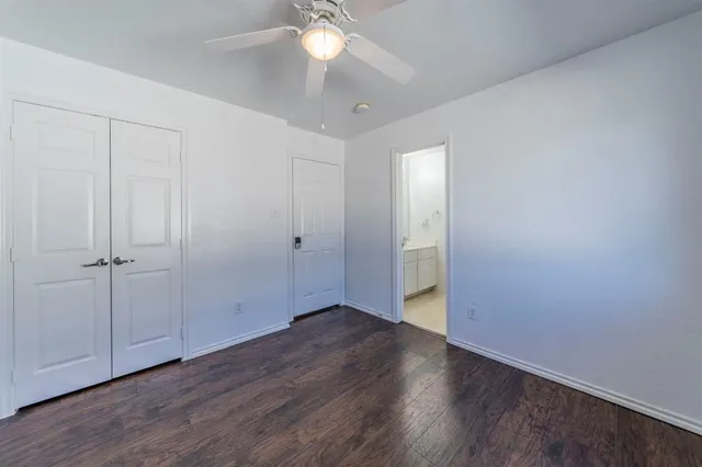 an empty room with wooden floor and fan