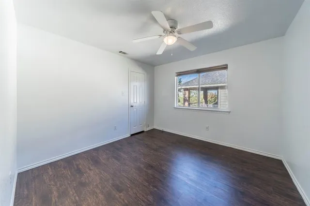 an empty room with wooden floor chandelier fan and windows