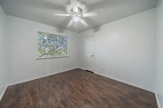 an empty room with wooden floor and fan