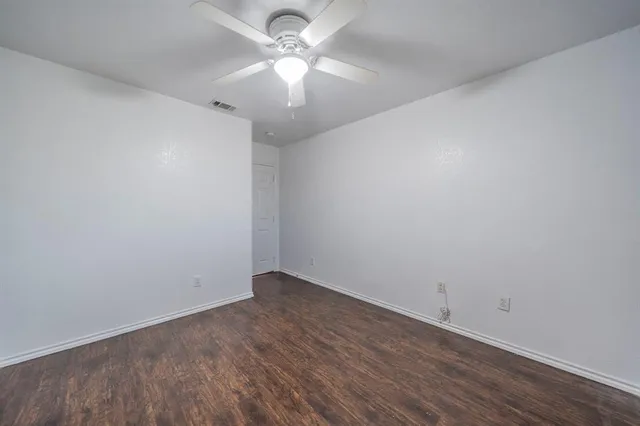an empty room with a window and a fan
