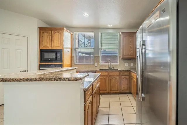 a kitchen with granite countertop a refrigerator and a sink
