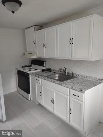 a kitchen with stainless steel appliances granite countertop a stove a sink and white cabinets