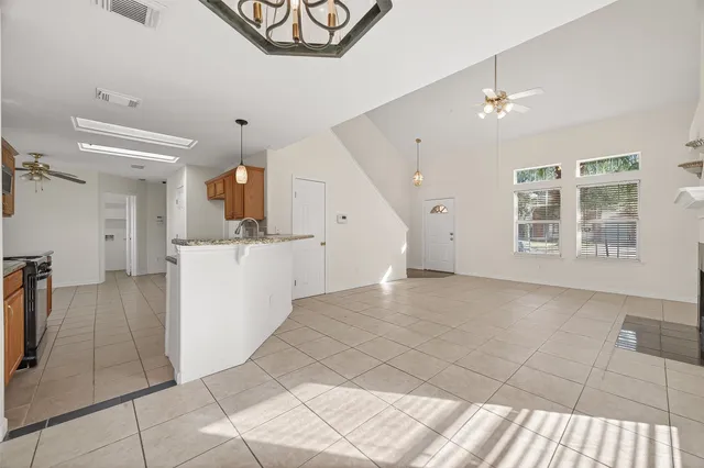 a view of an empty room with window and chandelier fan