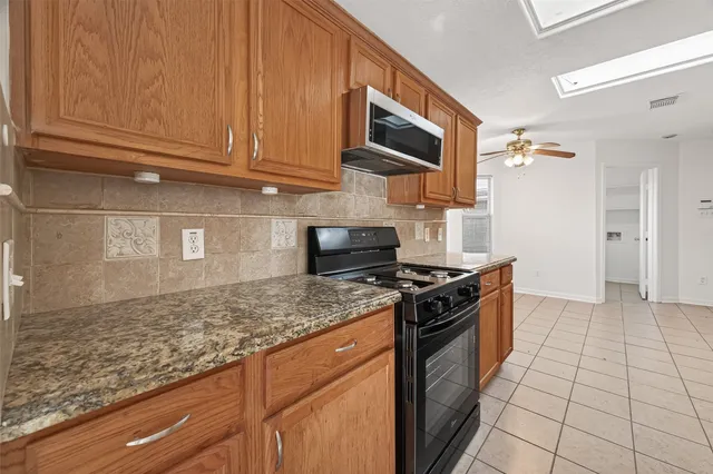an empty room with a chandelier fan and windows