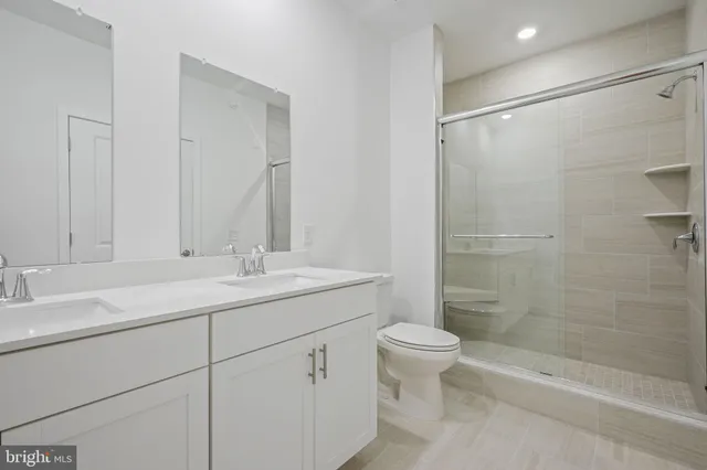 a bathroom with a shower sink vanity mirror and toilet