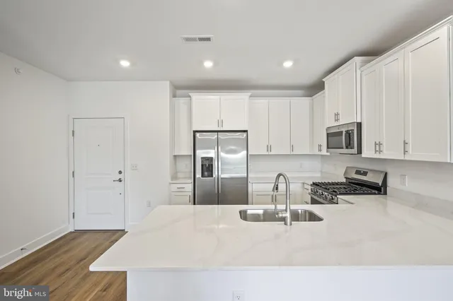 a kitchen with stainless steel appliances granite countertop a refrigerator sink and white cabinets