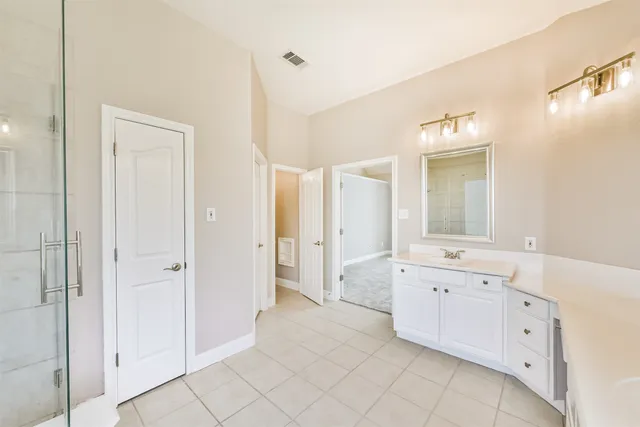 a large bathroom with a glass door shower a sink and mirror