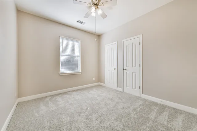 an empty room with a chandelier fan and windows