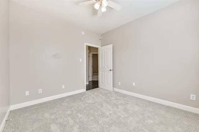 an empty room with a chandelier fan and closet area
