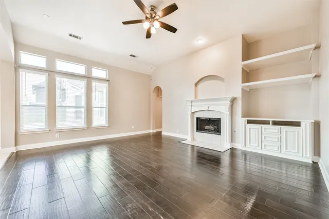 a view of an empty room with wooden floor fireplace and a window