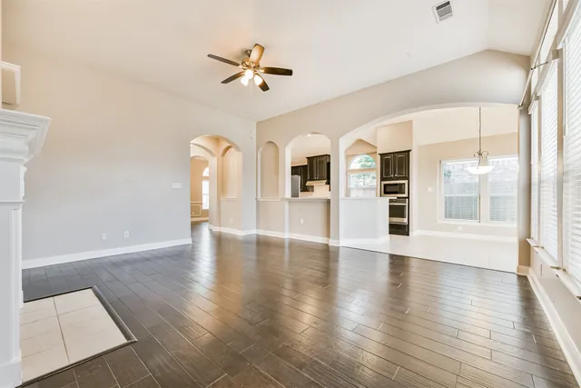 a view of empty room with wooden floor and fan