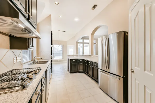 a kitchen with stainless steel appliances granite countertop a refrigerator a stove and a sink with wooden floor