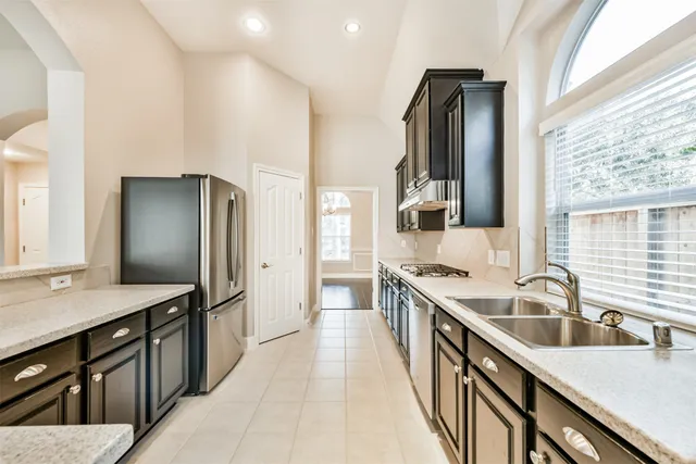 a kitchen with stainless steel appliances granite countertop a sink refrigerator and cabinets