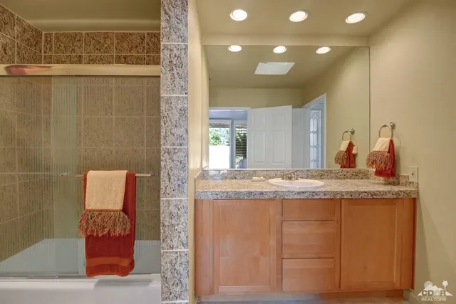 a bathroom with a granite countertop sink a toilet and mirror