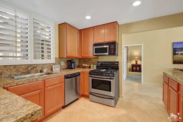 a kitchen with stainless steel appliances granite countertop a stove a sink and a microwave